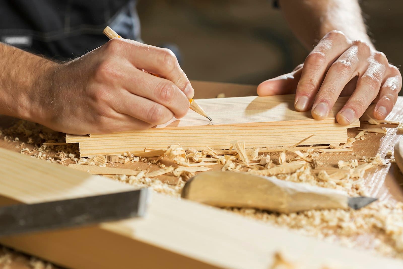 Carpenter marking a wooden board with a pencil
